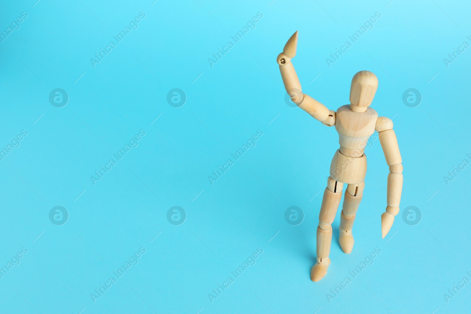 Photo of Wooden human model on light blue background, space for text. Mini mannequin