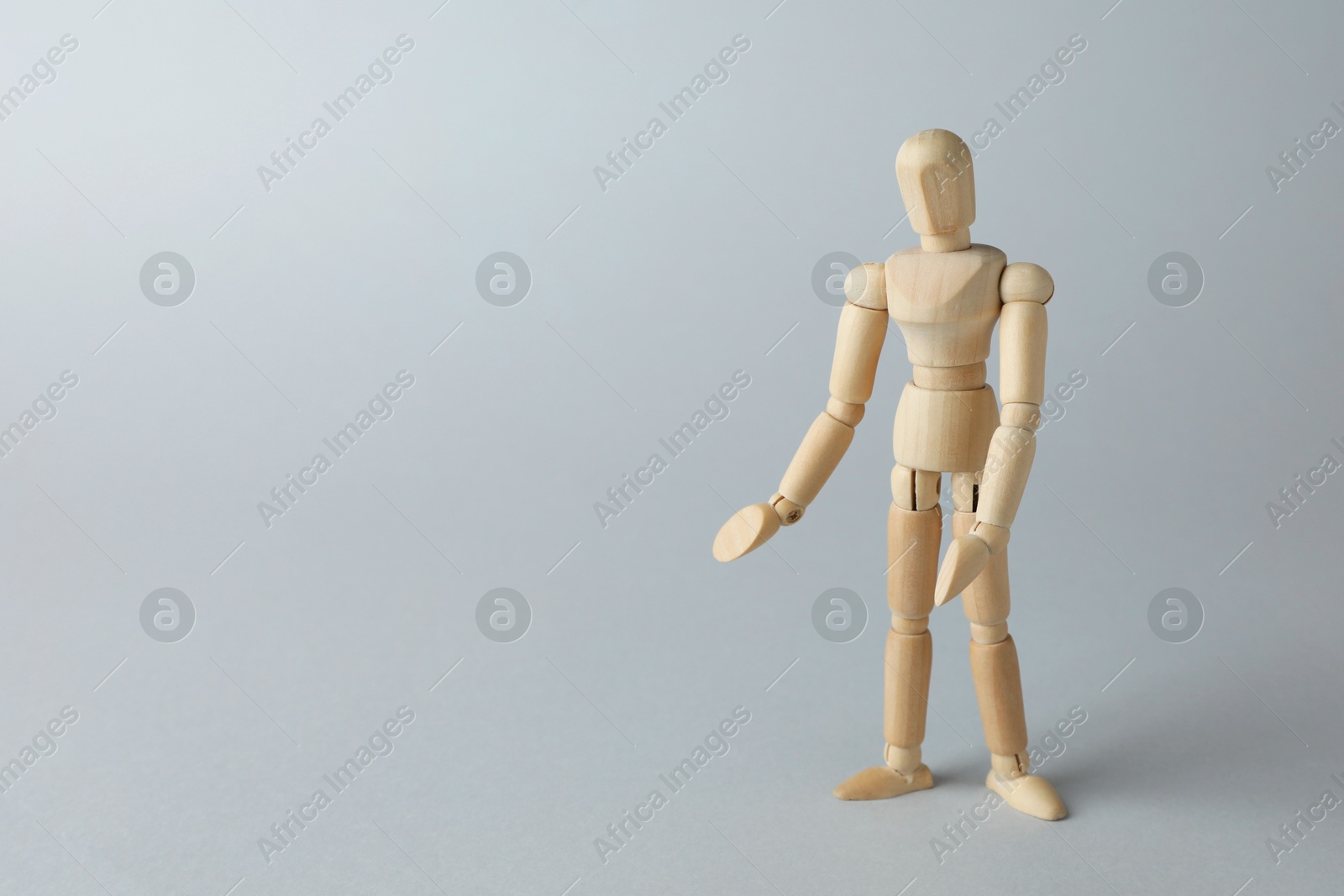 Photo of Wooden human model on grey background, space for text. Mini mannequin