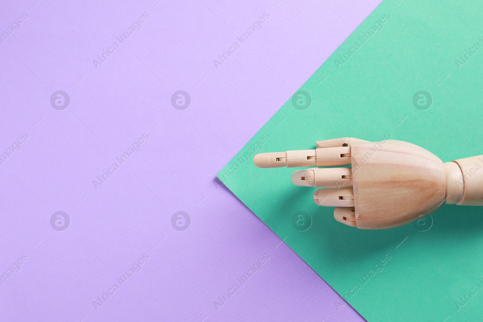 Photo of Wooden mannequin hand on color background, top view. Space for text