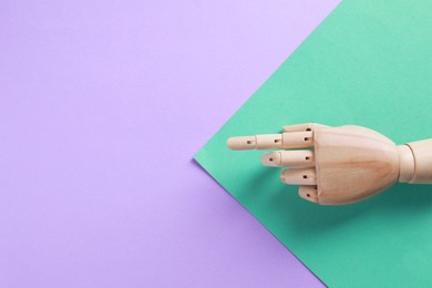 Photo of Wooden mannequin hand on color background, top view. Space for text