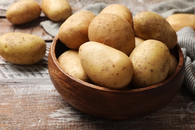 Photo of Many fresh potatoes in bowl on wooden rustic table, closeup