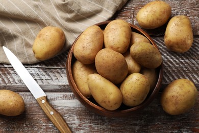 Many fresh potatoes, bowl and knife on wooden rustic table, flat lay