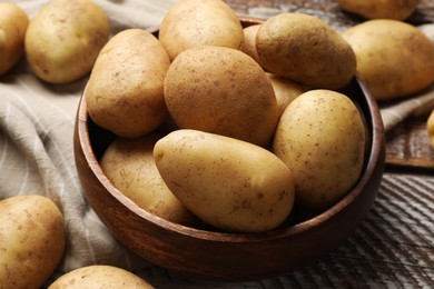 Photo of Many fresh potatoes in bowl on wooden rustic table, closeup