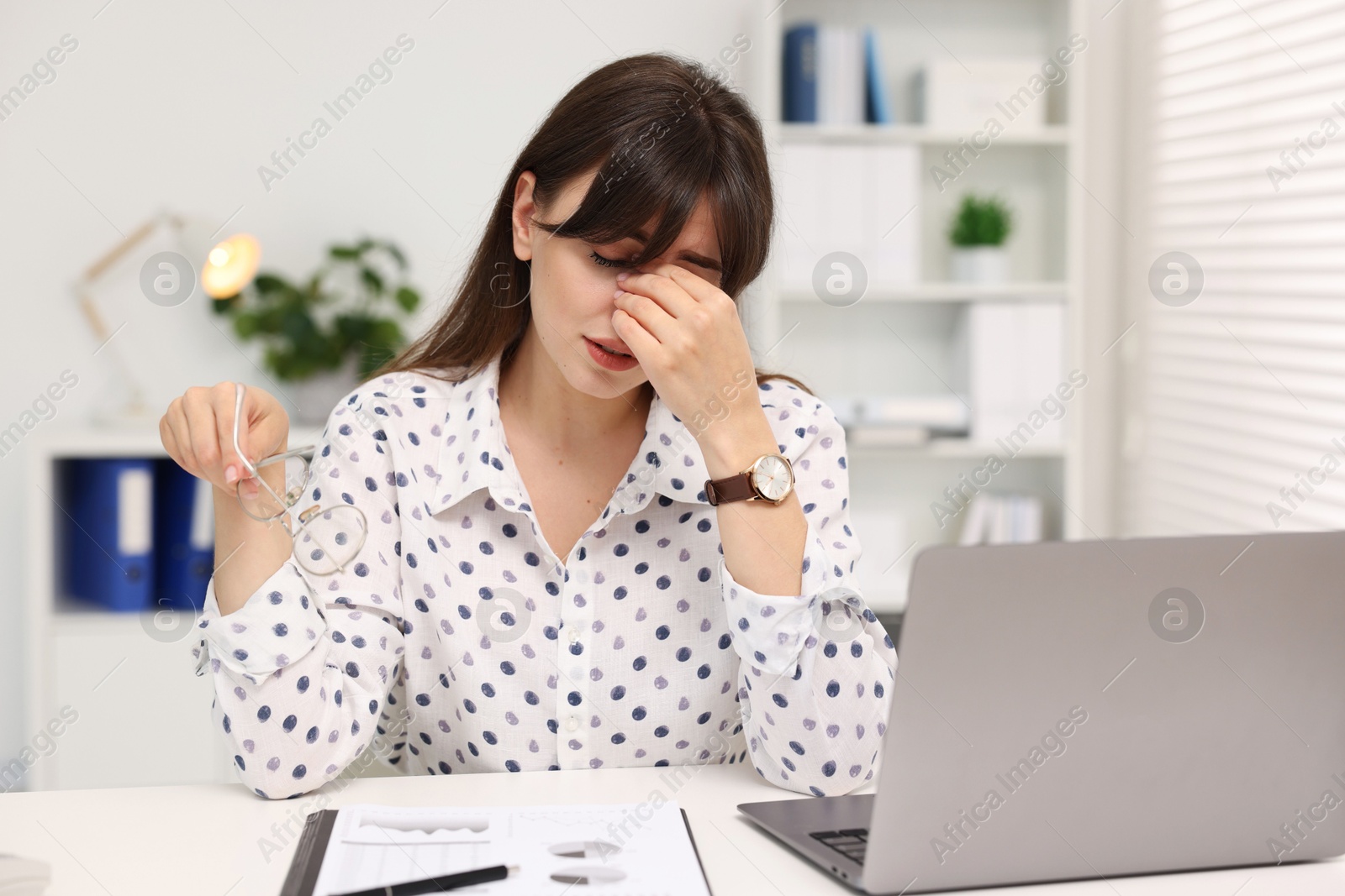 Photo of Overwhelmed woman sitting at table with laptop in office