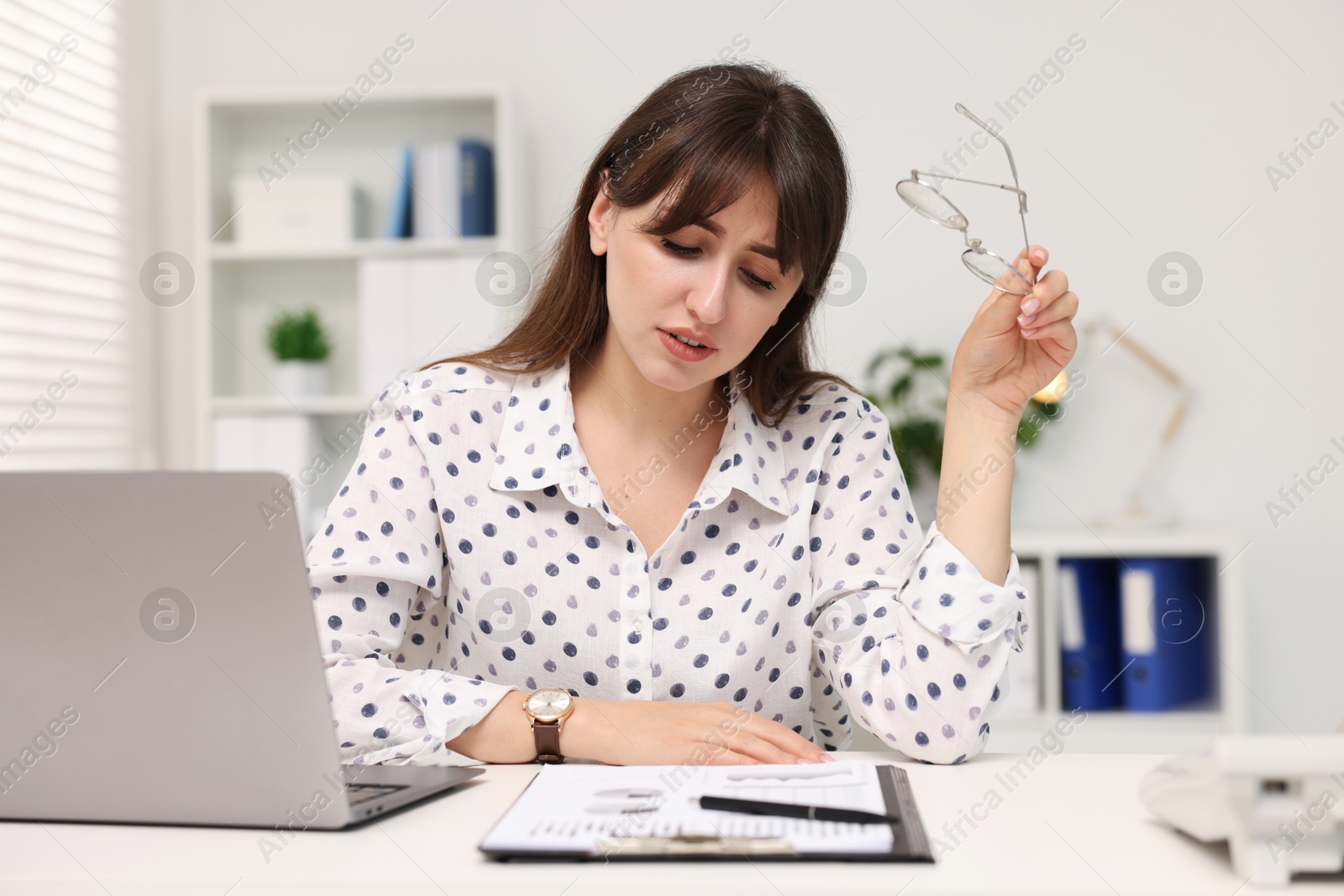 Photo of Overwhelmed woman sitting at table with laptop in office