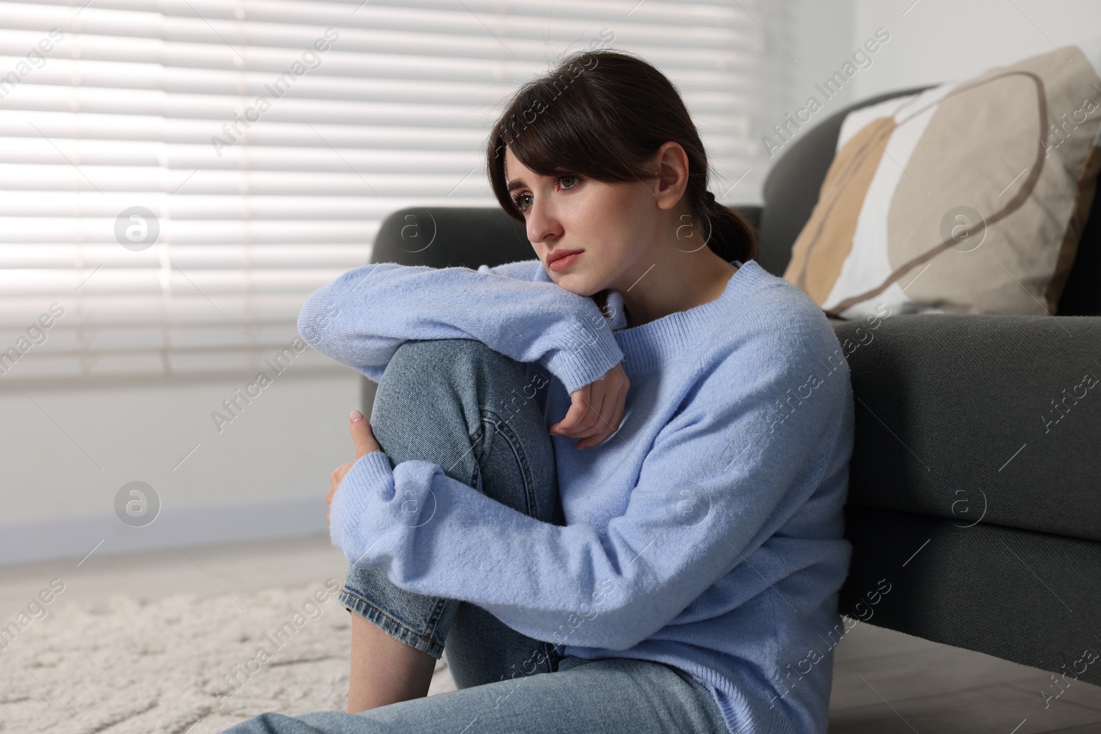 Photo of Loneliness concept. Sad woman sitting on floor at home