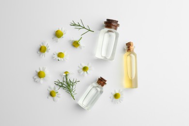 Photo of Aromatherapy. Essential oils and chamomiles on white background, flat lay