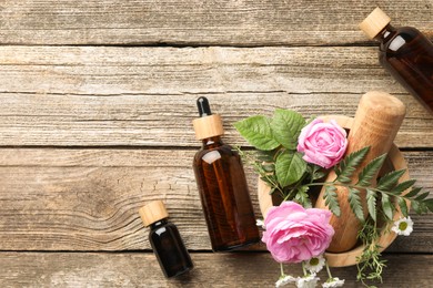 Photo of Aromatherapy. Different essential oils, flowers, mortar and pestle on wooden table, flat lay. Space for text