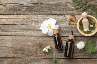 Photo of Aromatherapy. Different essential oils, flowers, green leaves, mortar and pestle on wooden table, flat lay. Space for text