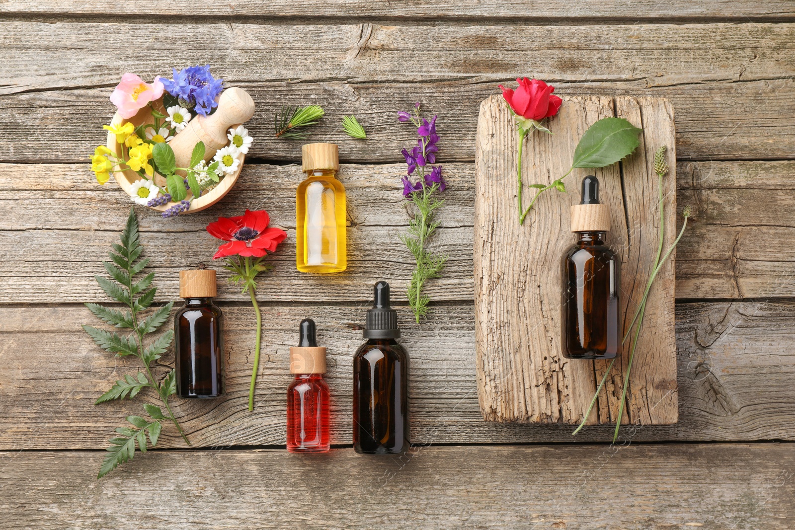 Photo of Aromatherapy. Different essential oils and flowers on wooden table, flat lay