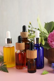 Photo of Aromatherapy. Different essential oils and flowers on pink table