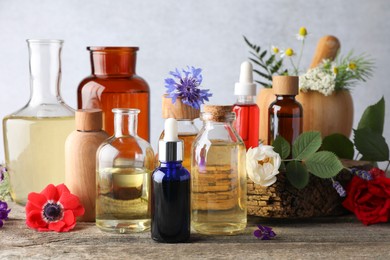 Photo of Aromatherapy. Different essential oils, flowers and green leaves on wooden table