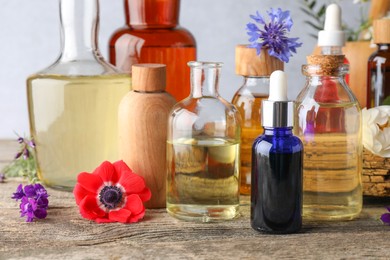 Aromatherapy. Different essential oils and flowers on wooden table