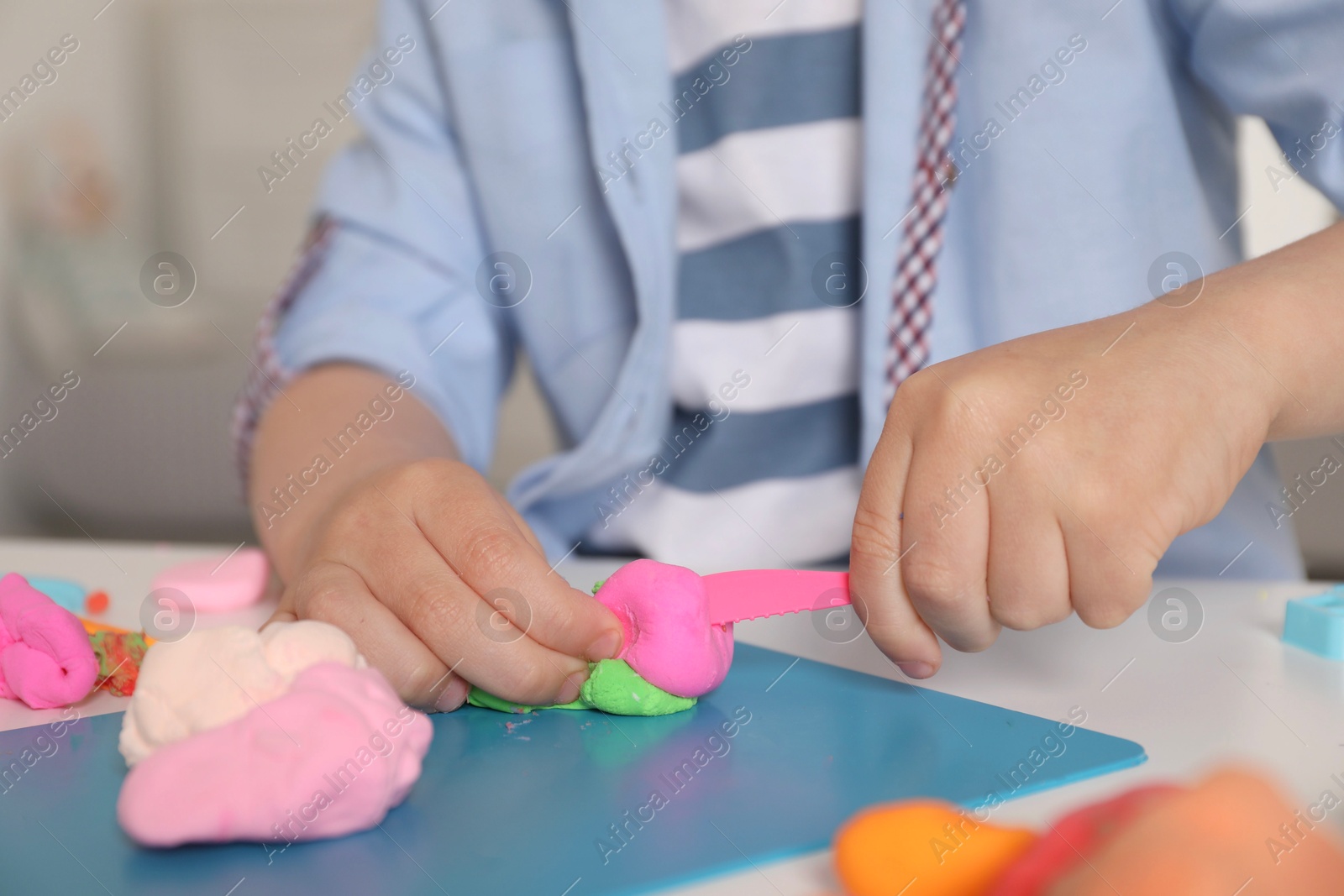 Photo of Little boy sculpting with play dough at table indoors, closeup