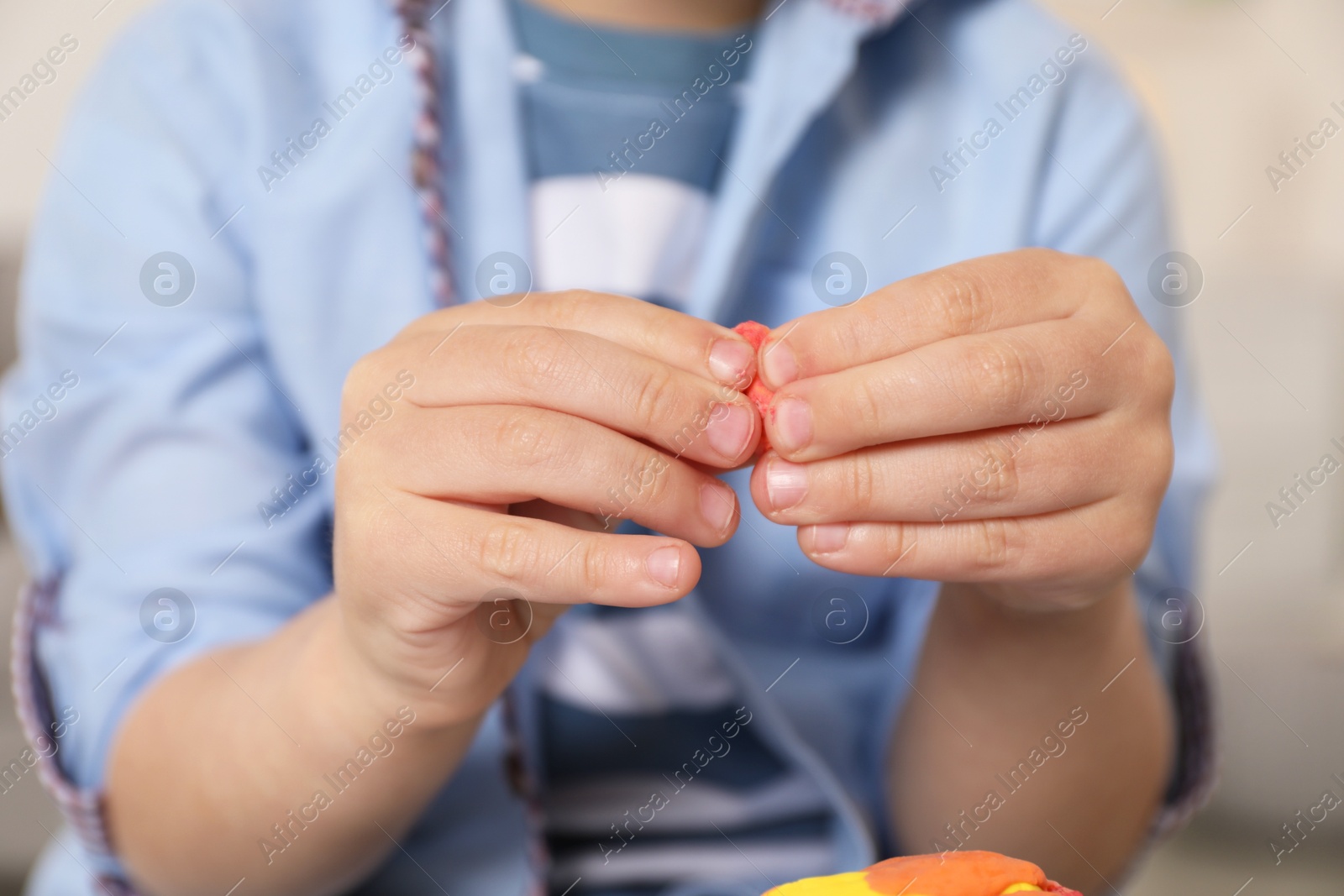 Photo of Little boy sculpting with play dough indoors, closeup