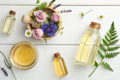 Photo of Aromatherapy. Different essential oils, green twig and flowers on white wooden table, flat lay