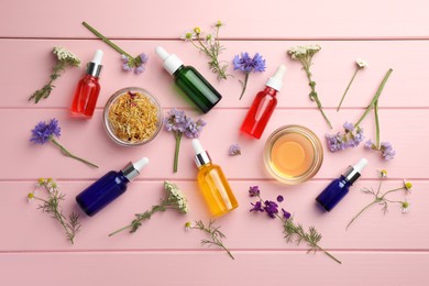 Photo of Aromatherapy. Different essential oils and flowers on pink wooden table, flat lay