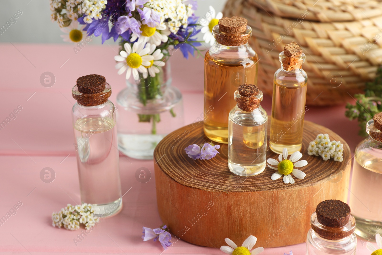 Photo of Aromatherapy. Different essential oils and flowers on pink wooden table