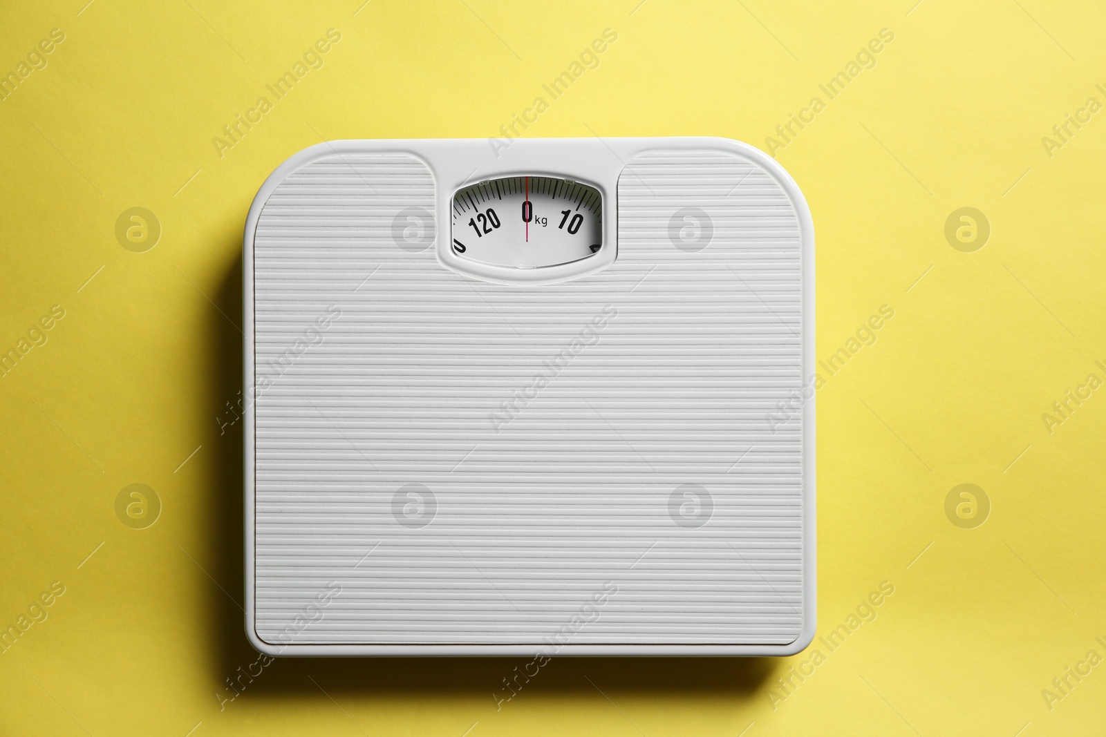 Photo of One bathroom scale on yellow background, top view