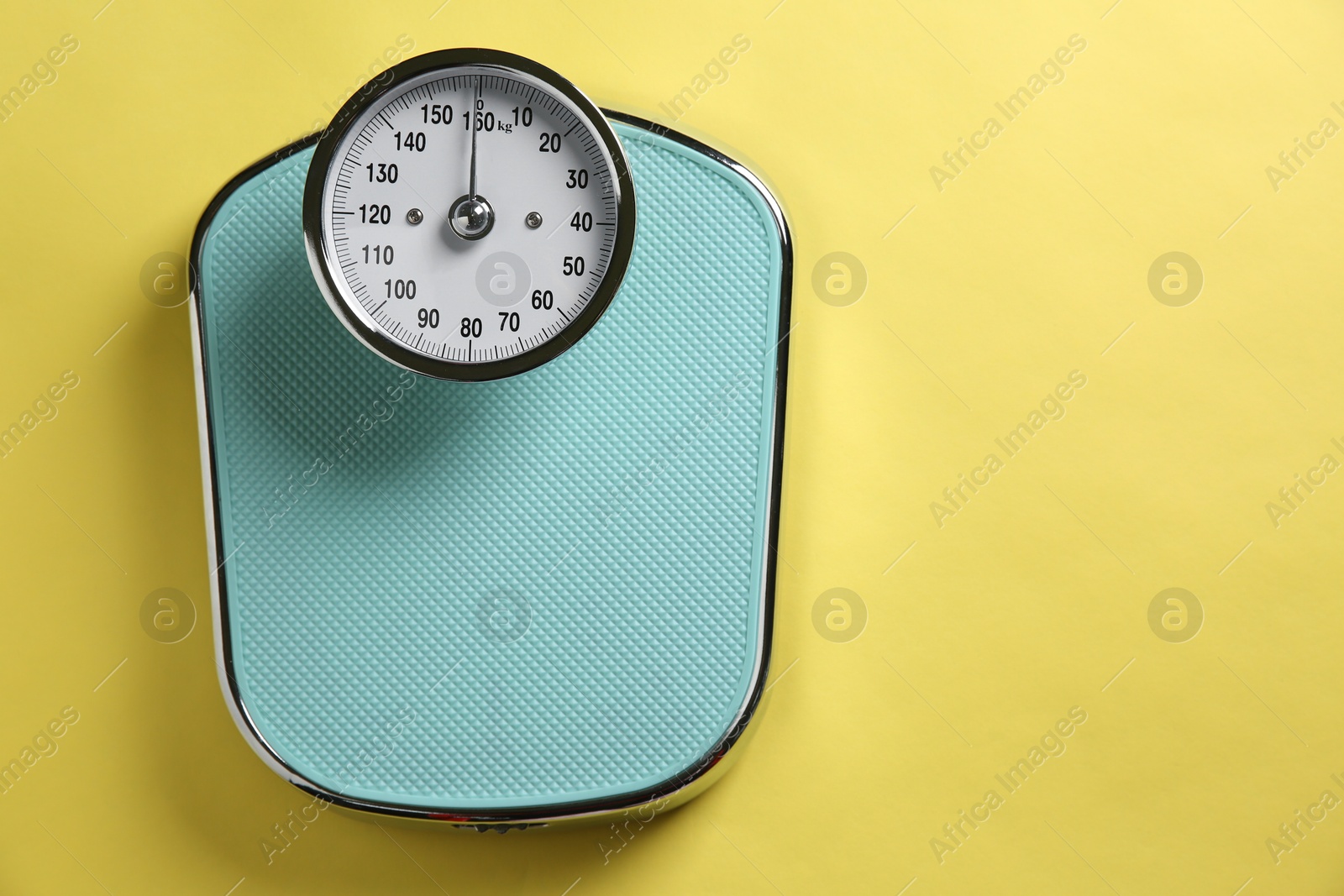 Photo of One bathroom scale on yellow background, top view. Space for text