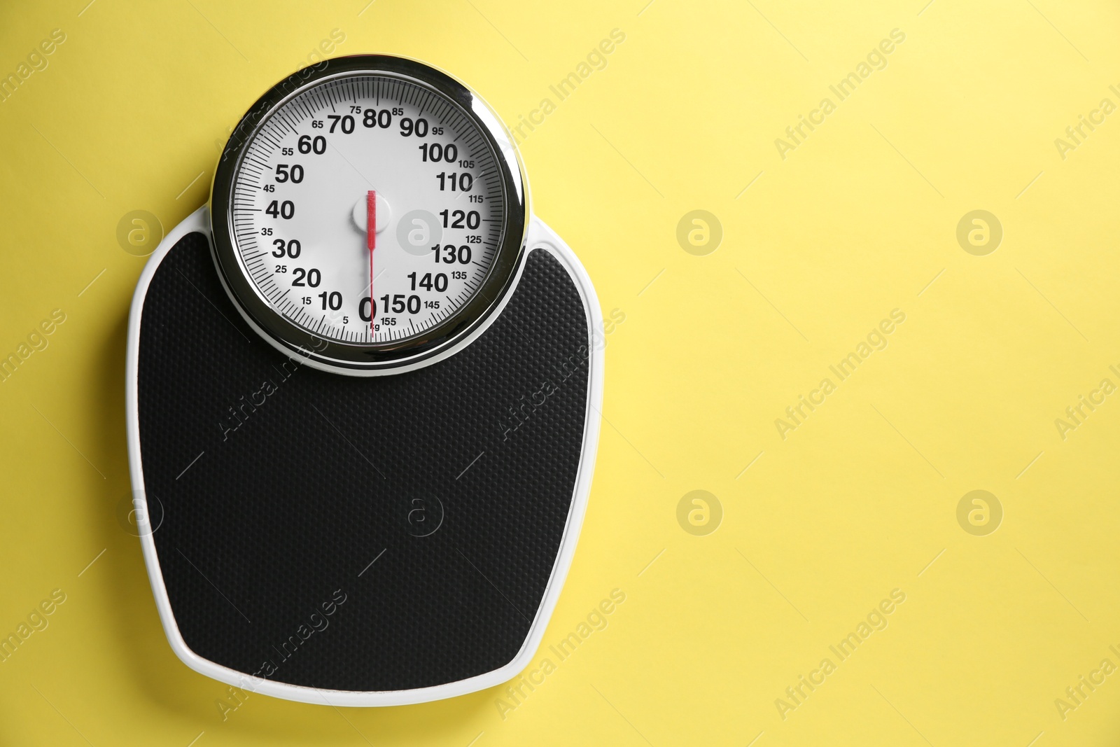 Photo of One bathroom scale on yellow background, top view. Space for text