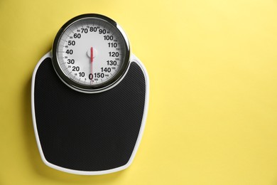 Photo of One bathroom scale on yellow background, top view. Space for text