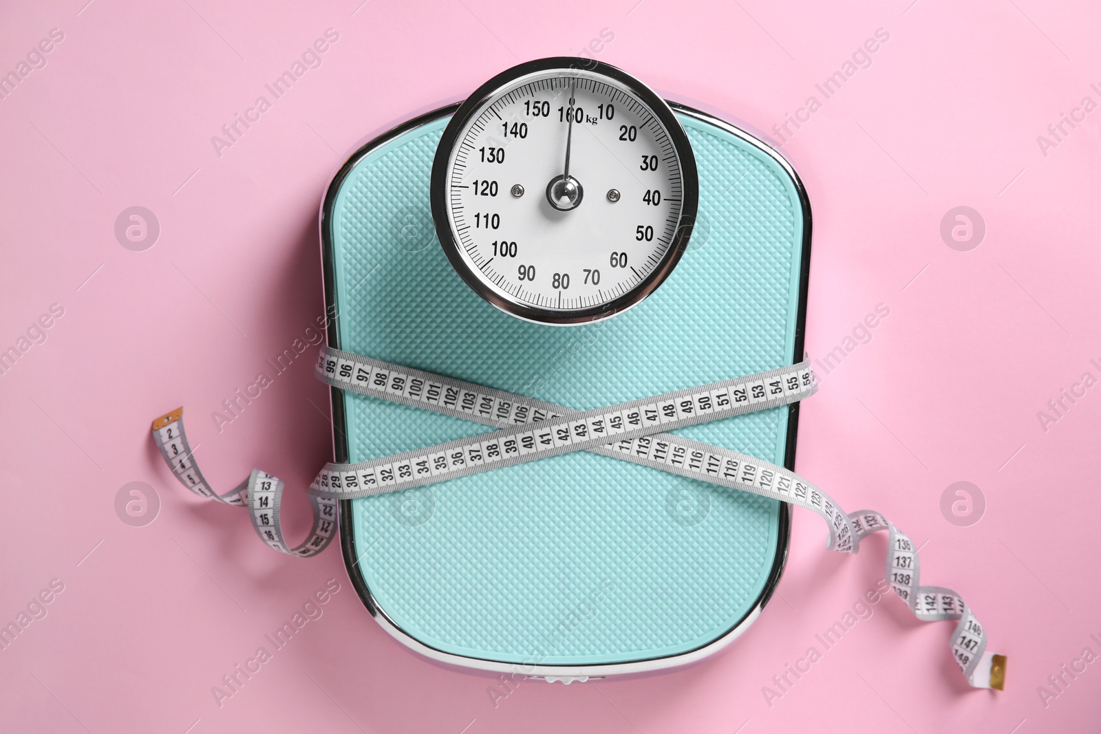 Photo of Scale tied with measuring tape on pink background, top view