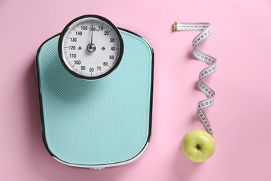 Photo of Scale, measuring tape and fresh apple on pink background, flat lay