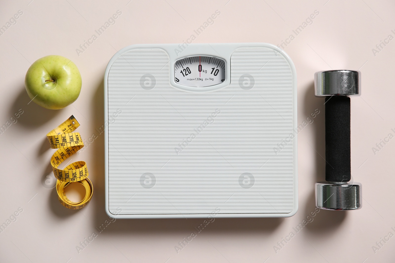 Photo of Scale, measuring tape, dumbbells and fresh apple on beige background, flat lay