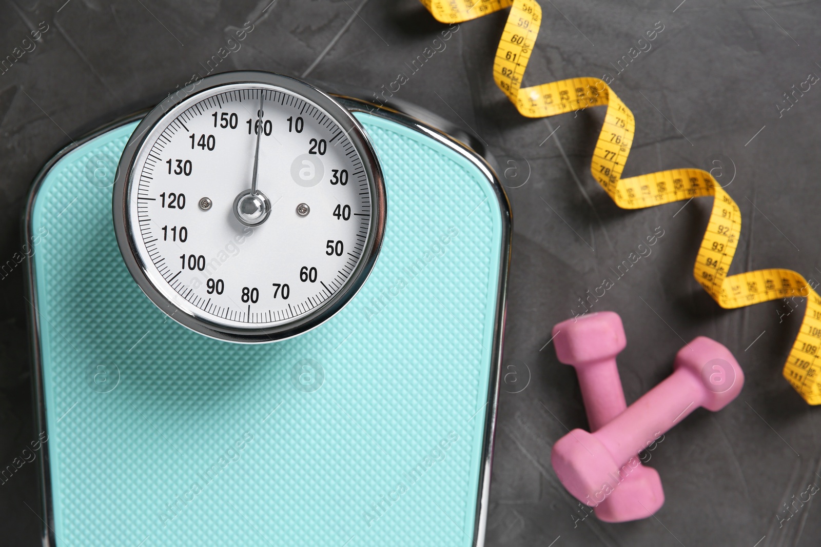 Photo of Bathroom scale, measuring tape and dumbbells on grey textured background, flat lay