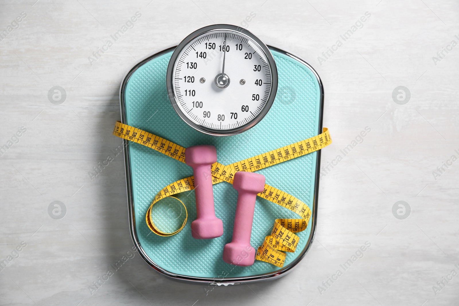 Photo of Bathroom scale, measuring tape and dumbbells on white wooden background, flat lay