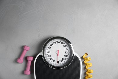 Photo of Bathroom scale, measuring tape and dumbbells on grey textured background, flat lay. Space for text