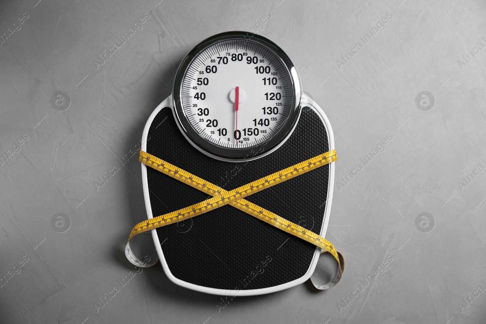 Photo of Scale tied with measuring tape on grey textured background, top view