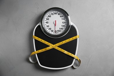 Photo of Scale tied with measuring tape on grey textured background, top view