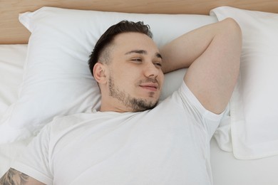 Photo of Bedtime. Handsome man lying in bed indoors, above view