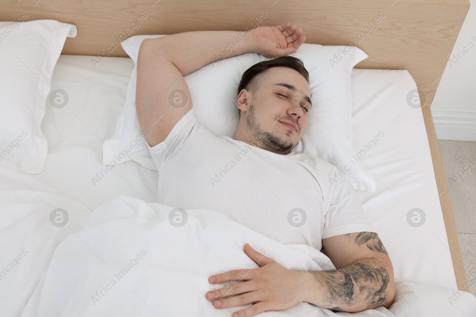 Photo of Bedtime. Handsome man sleeping in bed indoors, above view