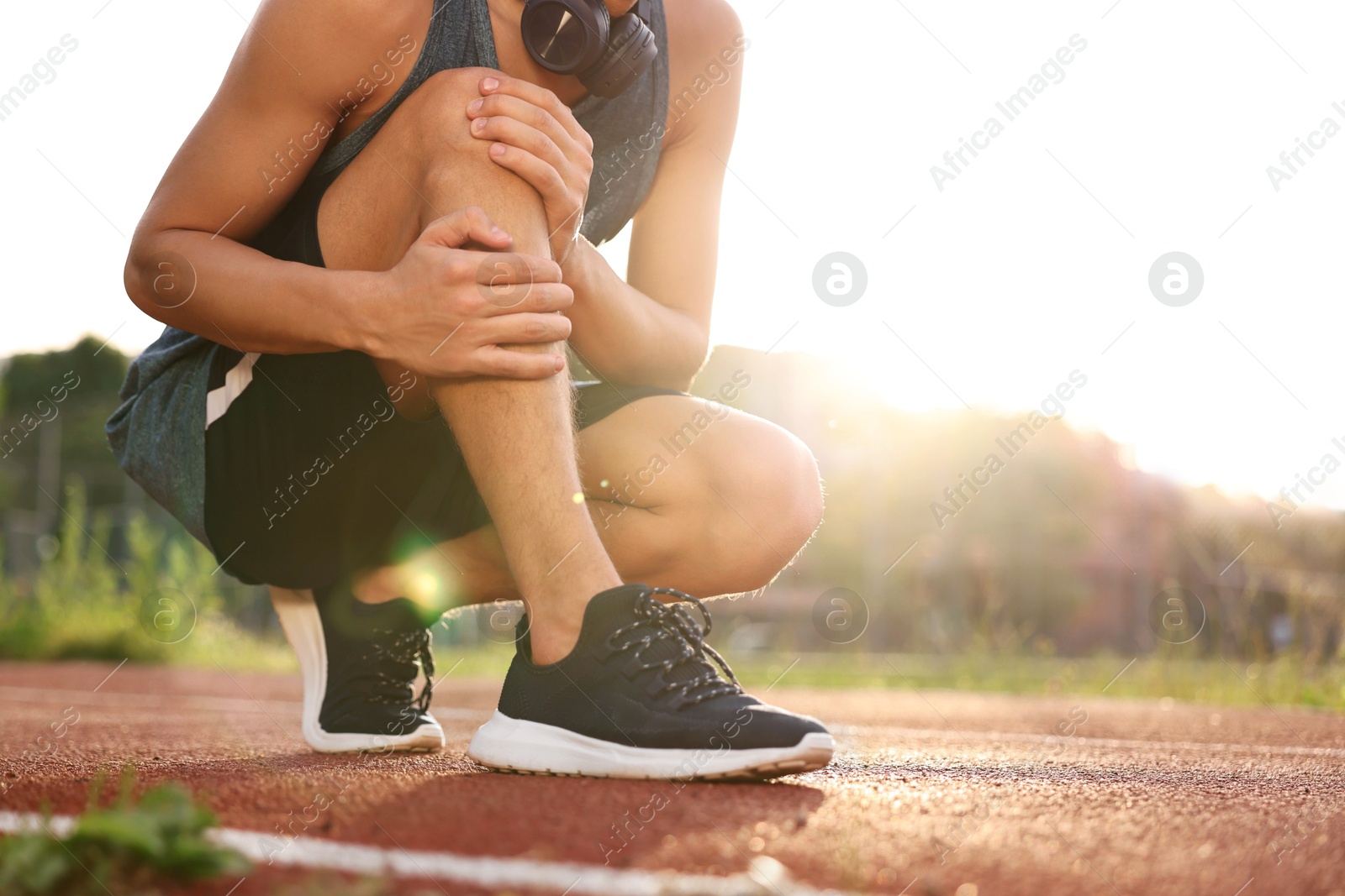 Photo of Sportsman with leg injury suffering from knee pain at stadium, closeup. Space for text