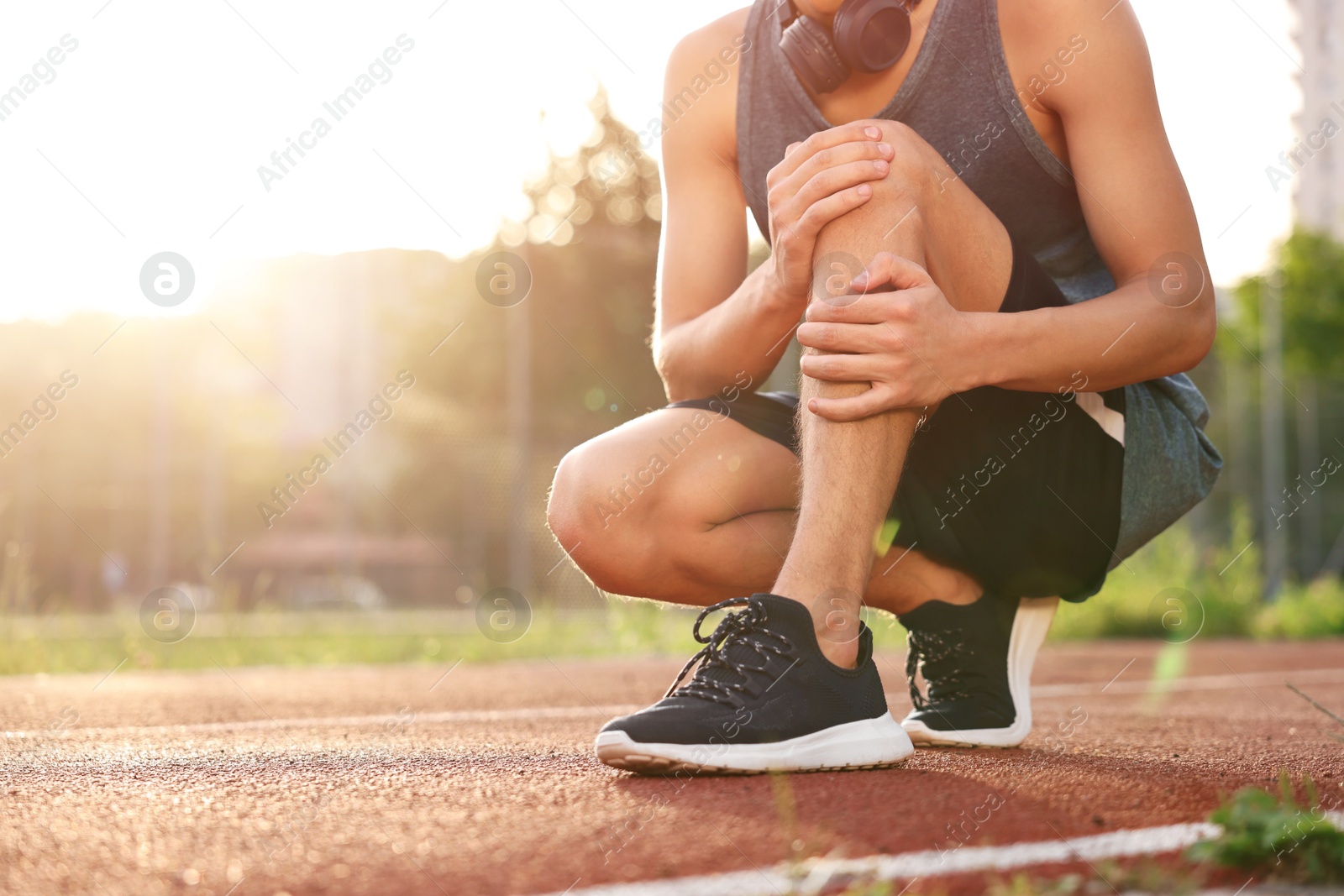 Photo of Sportsman with leg injury suffering from knee pain at stadium, closeup. Space for text