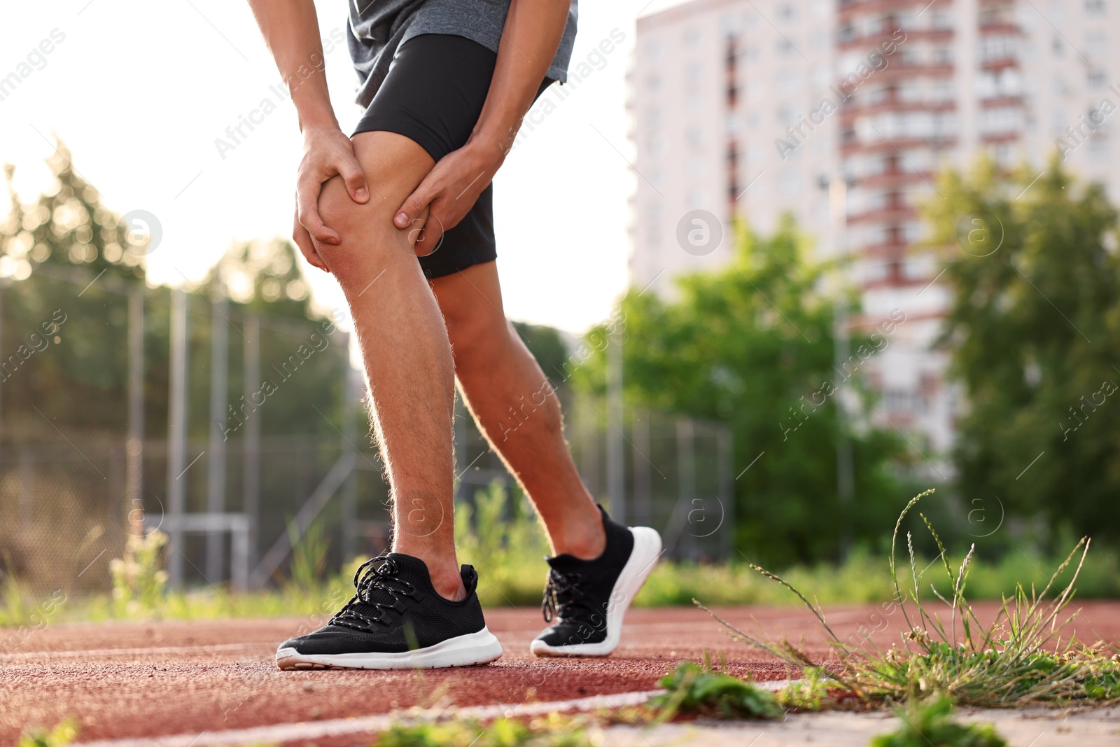 Photo of Sportsman with leg injury suffering from knee pain at stadium, closeup. Space for text