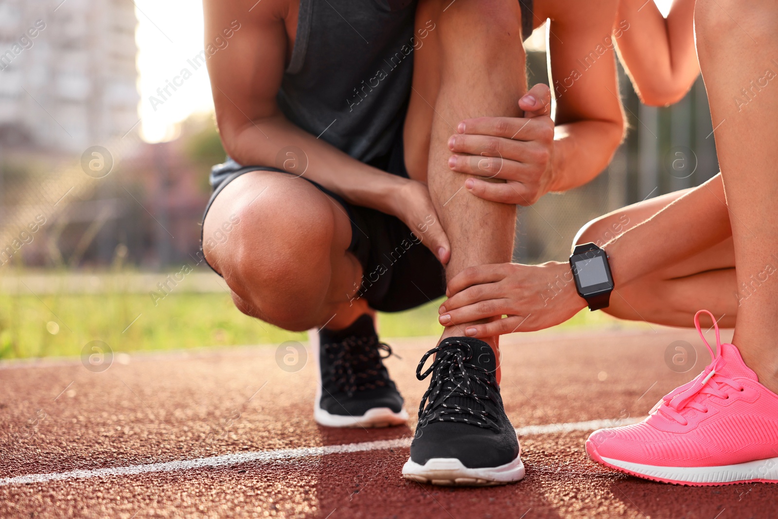 Photo of Sports injury. Woman helping man with leg pain at stadium, closeup