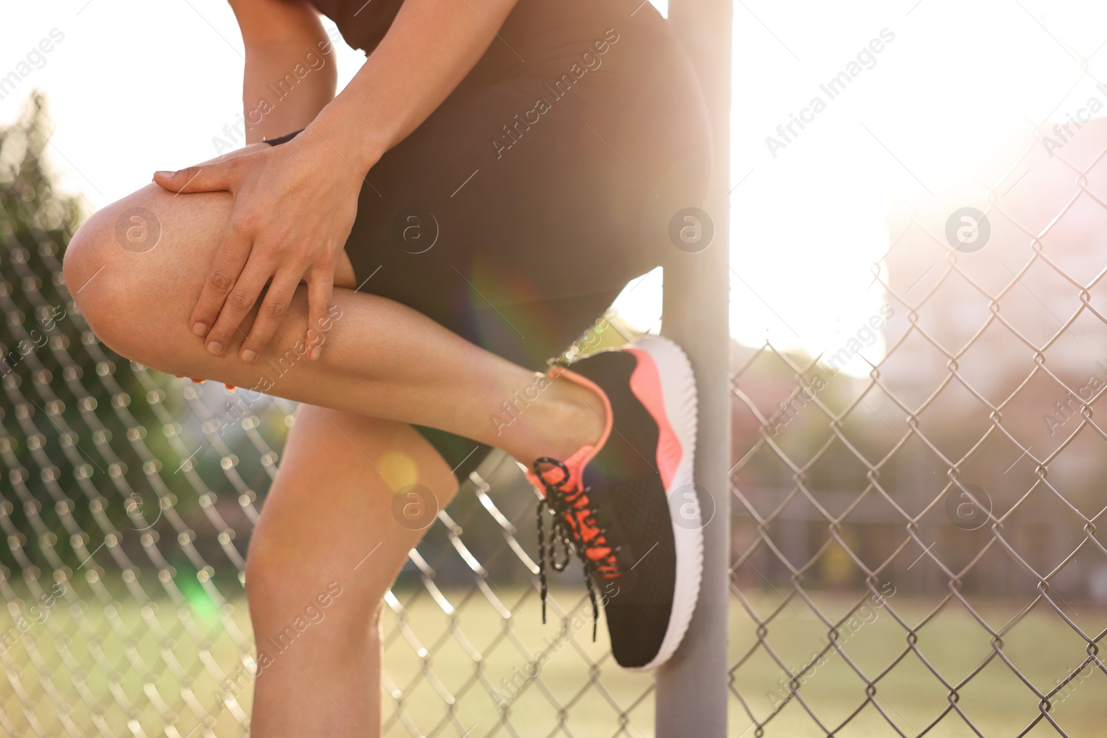 Photo of Sportswoman with leg injury suffering from knee pain at stadium, closeup