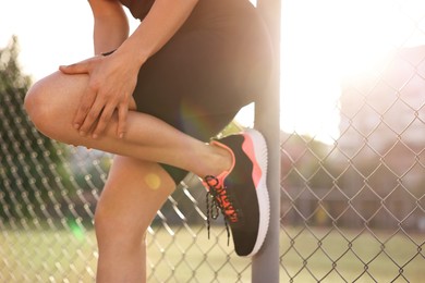 Photo of Sportswoman with leg injury suffering from knee pain at stadium, closeup