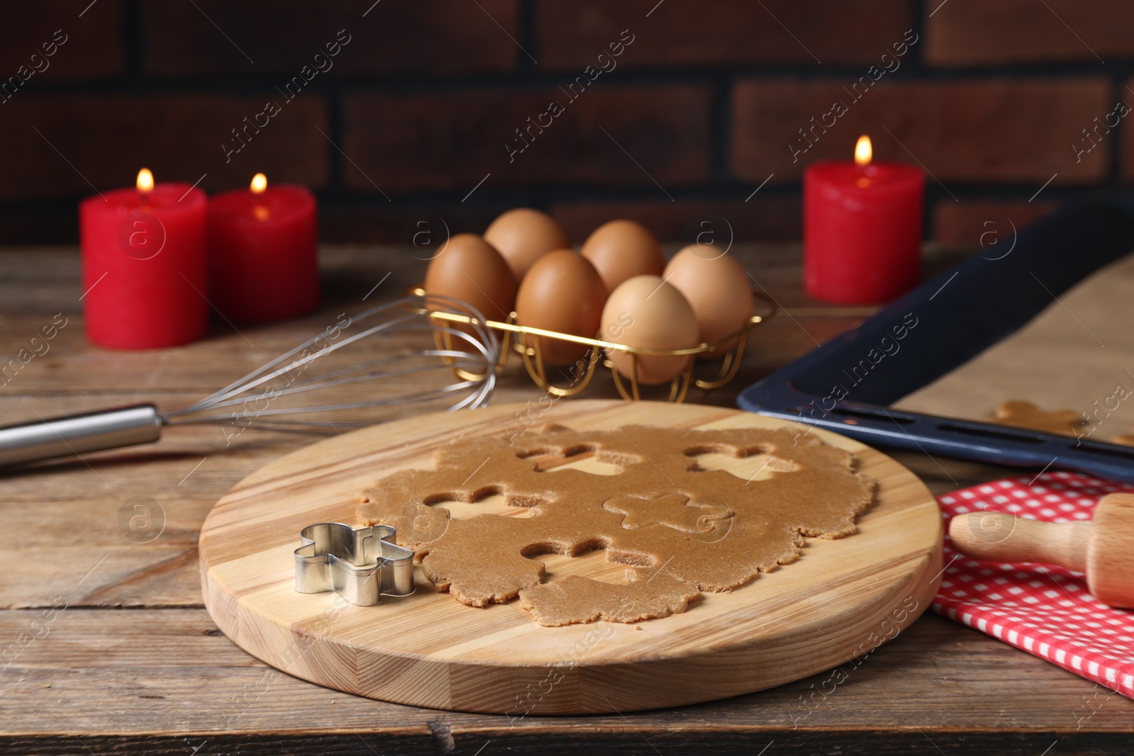 Photo of Raw dough, cookie cutter, whisk, eggs and burning candles on wooden table