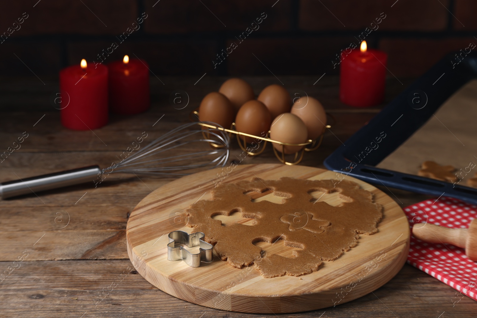 Photo of Raw dough, cookie cutter, whisk, eggs and burning candles on wooden table