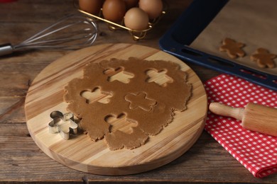 Photo of Raw dough, cookie cutter, whisk and rolling pin on wooden table