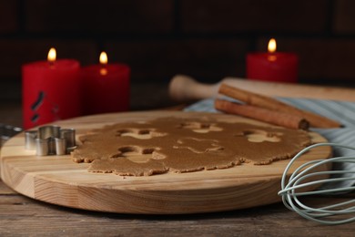 Photo of Raw dough, cookie cutter, whisk and burning candles on wooden table, closeup