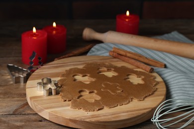 Photo of Raw dough, cookie cutters, whisk, rolling pin and burning candles on wooden table