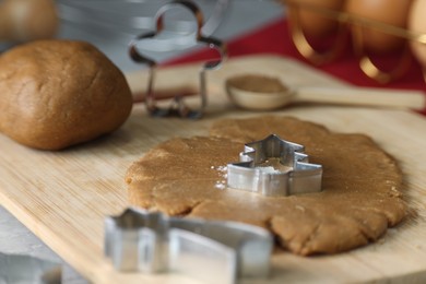 Raw dough and cookie cutters on table, closeup