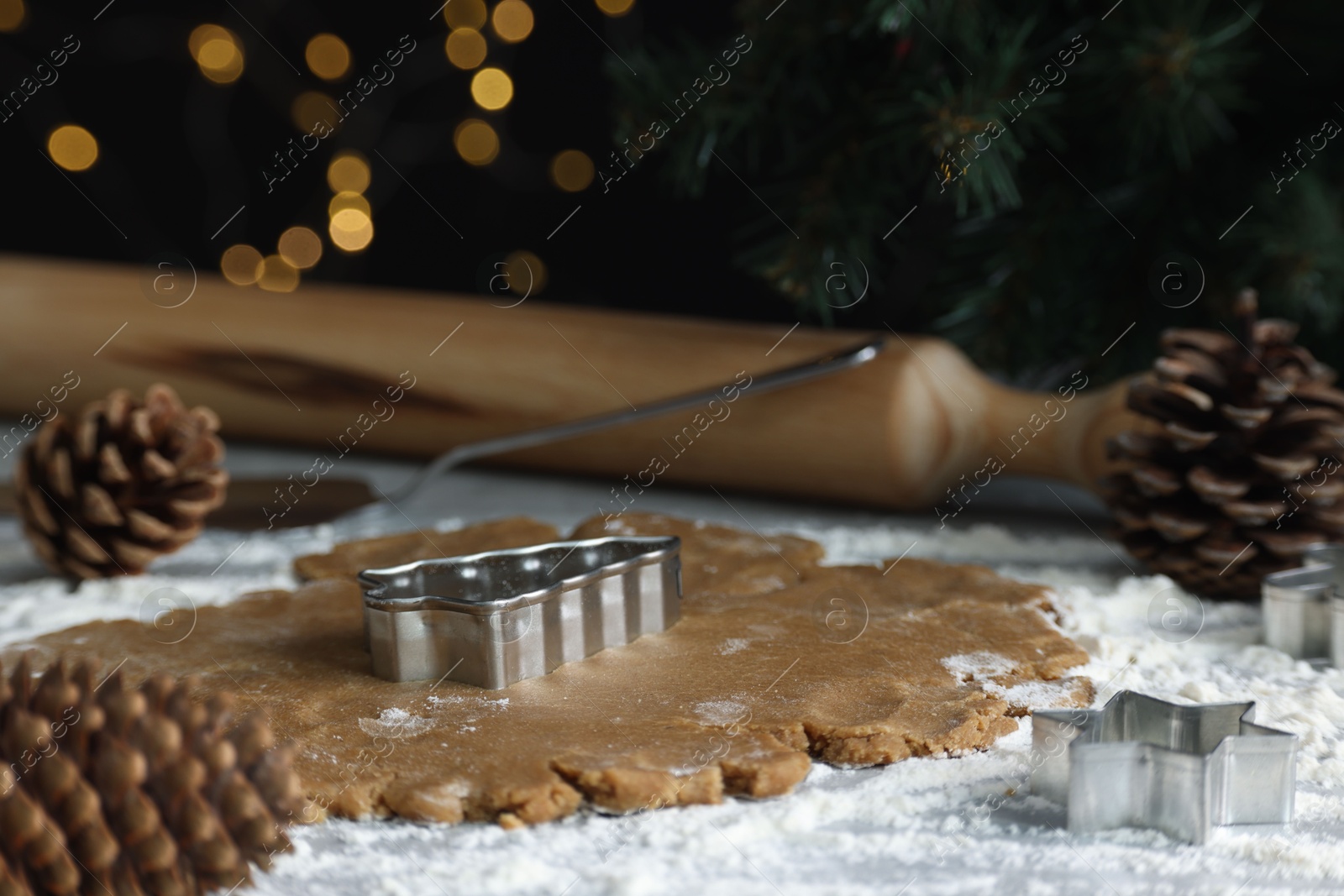 Photo of Raw dough, cookie cutters, pine cones and rolling pin on table, closeup