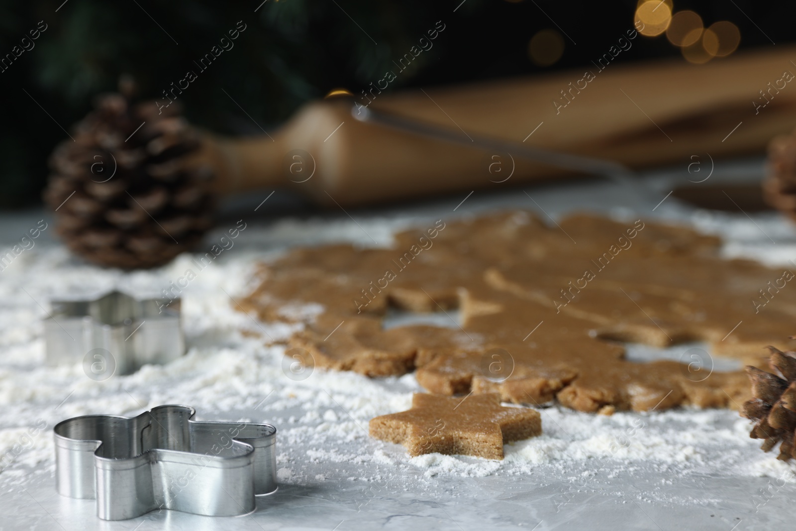 Photo of Raw dough and cookie cutters on grey table, closeup